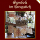 Cover des Buches 'Symbole im Kreuzstich' mit verschiedenen bestickten Stoffen auf und bei Blumengestellen mit Topfpflanzen daneben und dahinter