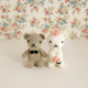 Zwei kleine Amigurumi-Pärchen als Hochzeitspaar, das vor einer bunten Blumentapete sitzt