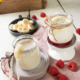 Zwei kleine Gläschen befüllt mit Bananenjoghurt und Mohnjoghurt, garniert mit Früchten