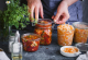 Vier verschiedene Gläser gefüllt mit Kimchi. Die Hände einer Person öffnen gerade eines davon.