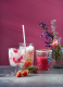 Drei verschiedene Cocktailgläser mit unterschiedlchen Kräutermocktails gefüllt, garniert mit Blüten und Früchten