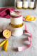 Kleines Gläschen mit Mango-Maracuja-Joghurt, daneben liegen zwei Hälften einer Maracuja und zwei Stücke Mango