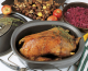 Wildgansbraten in einer ovalen Ofenform, daneben ein Topf mit Rotkraut, sowie Kastanien auf einem Backblech