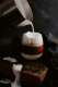 Ein Glas mit Irish Coffee, in das gerade Milch geschüttet wird