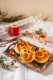 Drei Neujahrsschweinchen aus Germteig liegen auf einem Holztablett, daneben liegen kleine Glücksbringer