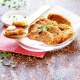 Ein Glasteller auf rot/weißer Serviette mit mehreren Getreideschnitzel, darauf liegt ein Holzkochlöffel, auf dem zwei kleine Stücke des Schnitzels liegen