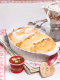 Eine weiße Auflaufform mit den Salzburger Nockerl, die auf einer bunten Serviette drapiert ist. Die Nockerl sind mit Zucker bestreut