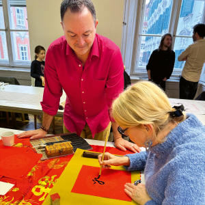 Abbildung von Gastautor Martin Veigl und Teilnehmerin bei Tao-Kalligraphie