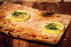 Ein Stück Zitronenflammkuchen garniert mit zwei Scheiben Zitrone auf einem Holzbrett
