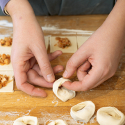 zwei Hände, die die Tortellini-Teigenden festdrücken