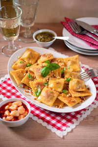 Gutenfreie Ravioli angerichtet auf einem weißen Teller auf einem gedeckten Tisch