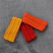 drei Kinderstirnbände nebeneinande liegend, eines in gelb, eines in orange und eines in rot