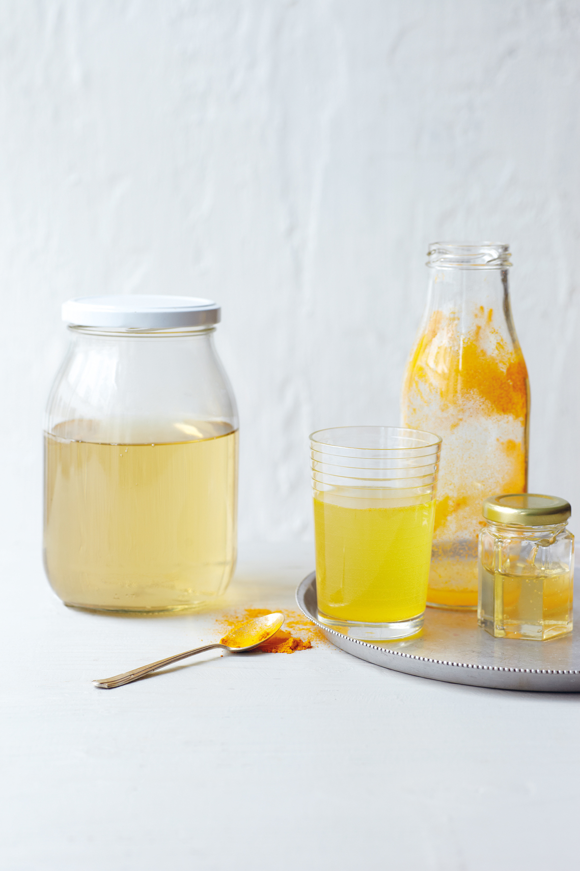 Mehrere Gläser gefüllt mit Kombucha auf einem silbernen Tablett
