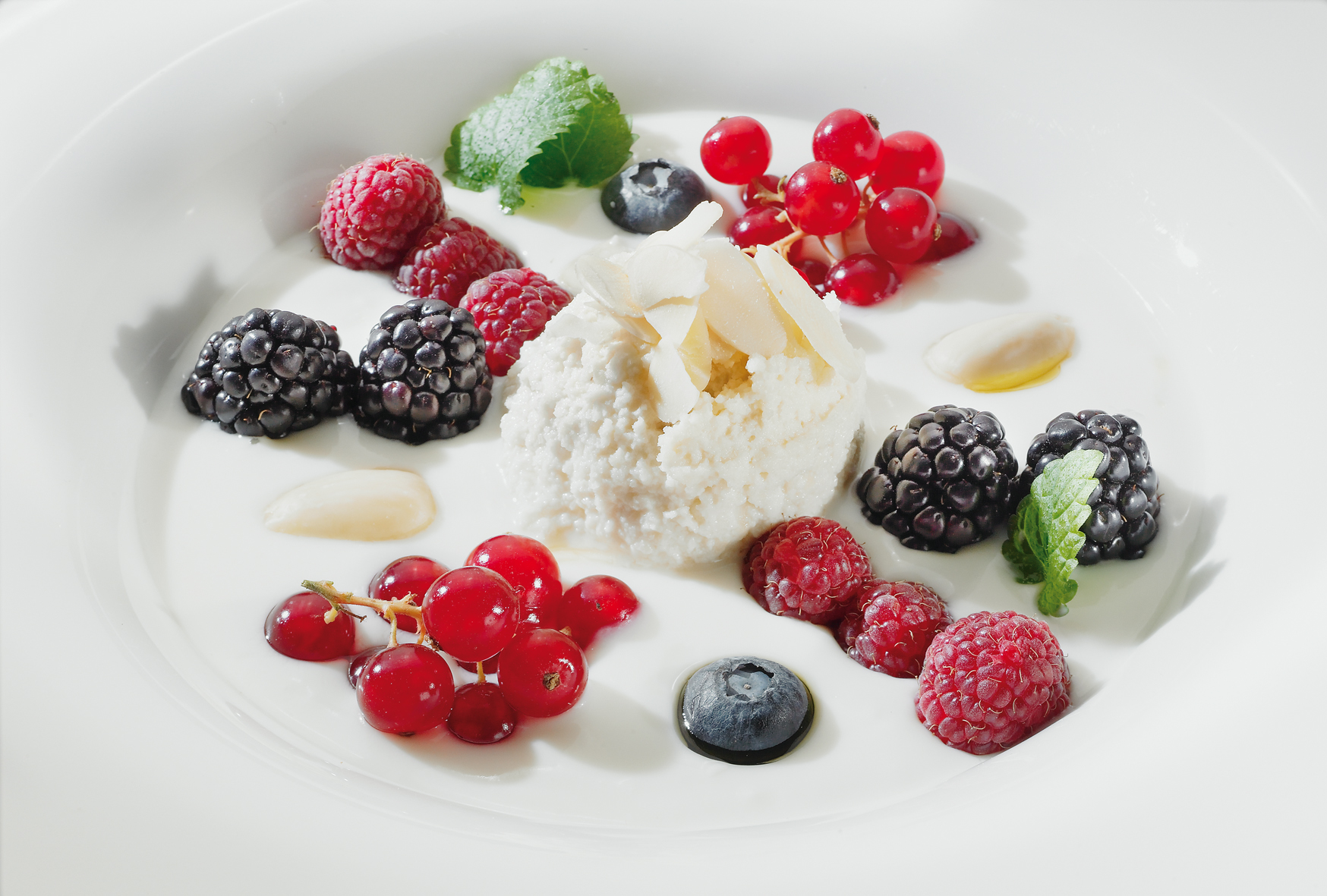 Leinöljughurt angerichtet in einer weißen Schale mit Mandelmus und frischen Beeren dekoriert