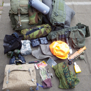 Verschieden Austrüstungsteile für die Jagd, wie ein Rucksack, ein Fernglas, ein Hut, ein Schlafsack und Insektenschutz.