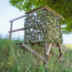 Eine Reviereinrichtung im Wald die mit Blättern getarnt ist.