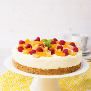 cremig-fruchtige Torte auf weißem Tortenteller platziert, garniert mit vielen Früchten