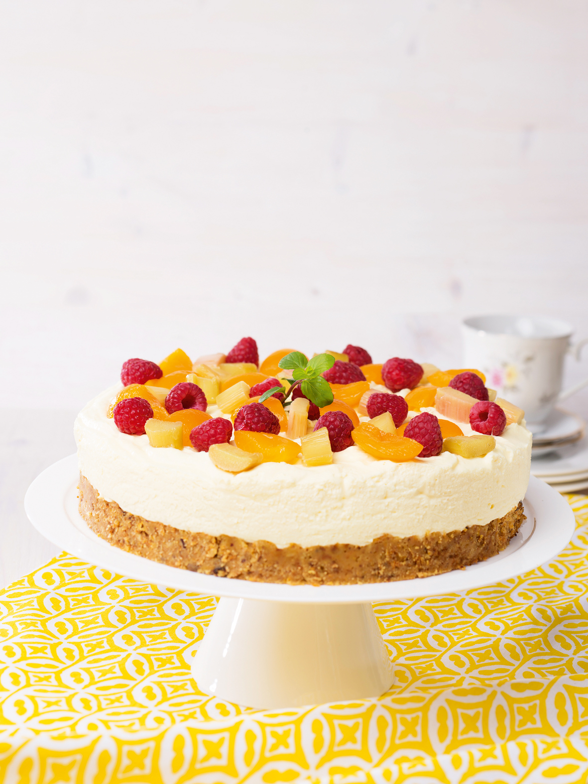 cremig-fruchtige Torte auf weißem Tortenteller platziert, garniert mit vielen Früchten