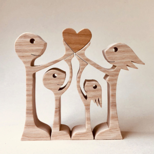 Vier Holzfiguren die gemeinsam ein Herz in den Händen halten
