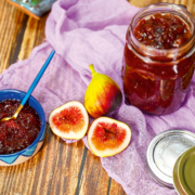 Auf einem lila Tischtuch steht ein volles Glas mit Feigenauftstrich, daneben steht ein kleines Schälchen mit demselben Aufstrich. Weiters liegt eine ganze und eine halbierte Feige daneben.