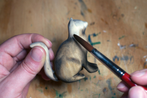 Eine aus Holz geschnitzte Katze wird mit Farbe bemalt Eine aus Holz geschnitzte Katze wird mit Farbe bemalt