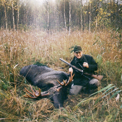 Der Autor sitzt mit einer Jagdwaffe neben einem ausgestopften Tier