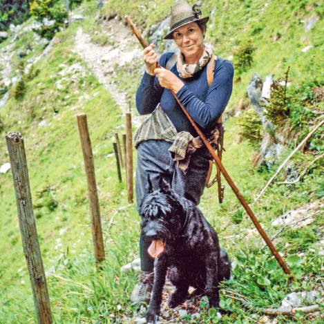 Eine Jägerin mit einem Hund steht auf einer Wiese