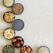 Insgesamt neun schwarze kleine Schälchen, die verschiedene Samen und Nüsse enthalten. Es sind Walnüsse, Mandeln, Haselnüsse, Leinsamen, Hanfsamen, Maroni, Mohn, Sonnenblumen- und Kürbikerne.