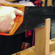 Mit einer Handsäge wird bei einem Holzstück entlang der Linie gesägt