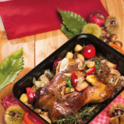 Eine gebratene Gans mit Gemüse liegt in einer rechteckigen Kaserolle.