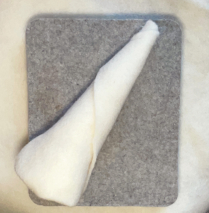 Fantastisches Nadelfilzen36_C_Claudia Marie Lenart -4a Ein weißer Kegel aus Filz, der auf einem grauen Stück Filz liegt.