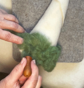 Fantastisches Nadelfilzen36_C_Claudia Marie Lenart -5a Auf einem weißen Filzkegel wird am unteren Rand grüne Wolle, die in Falten gelegt wird, angfilzt.