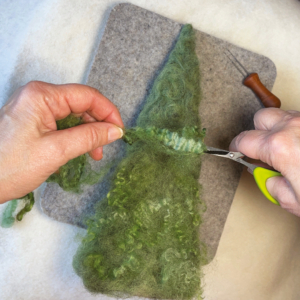 Fantastisches Nadelfilzen37_C_Claudia Marie Lenart -8 Eine grüne Locke wird zurechtgeschnitten und auf den Baum arrangiert. Daneben liegt eine Filznadel