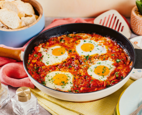 Das Shakshuka mit vier Eiern wurde in einer Pfanne angerichtet, die auf einem Tisch steht