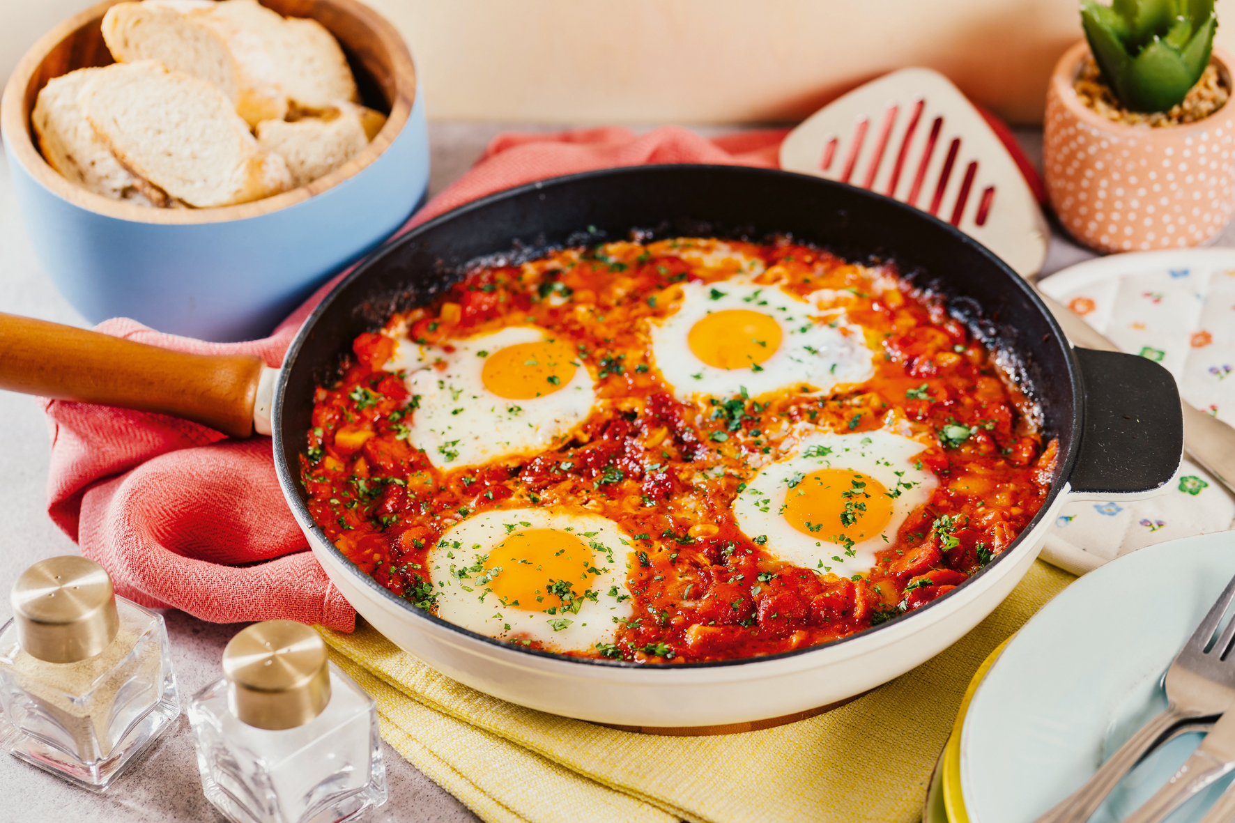 Das Shakshuka mit vier Eiern wurde in einer Pfanne angerichtet, die auf einem Tisch steht