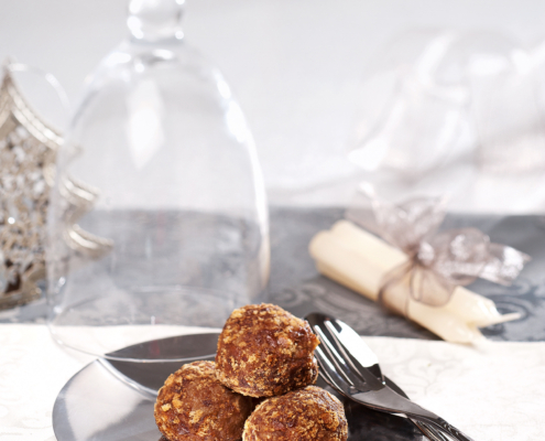 Auf einem weihnachlich dekorierten Tisch steht ein Teller mit drei Lebkuchenknödel, daneben liegt ein Besteck