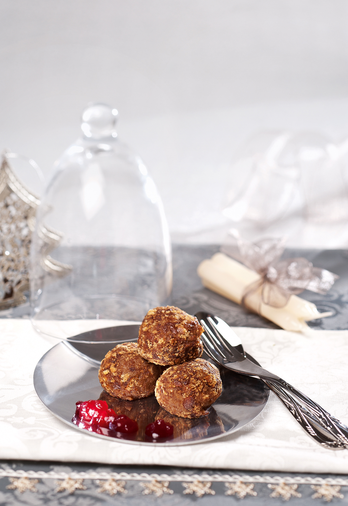 Auf einem weihnachlich dekorierten Tisch steht ein Teller mit drei Lebkuchenknödel, daneben liegt ein Besteck