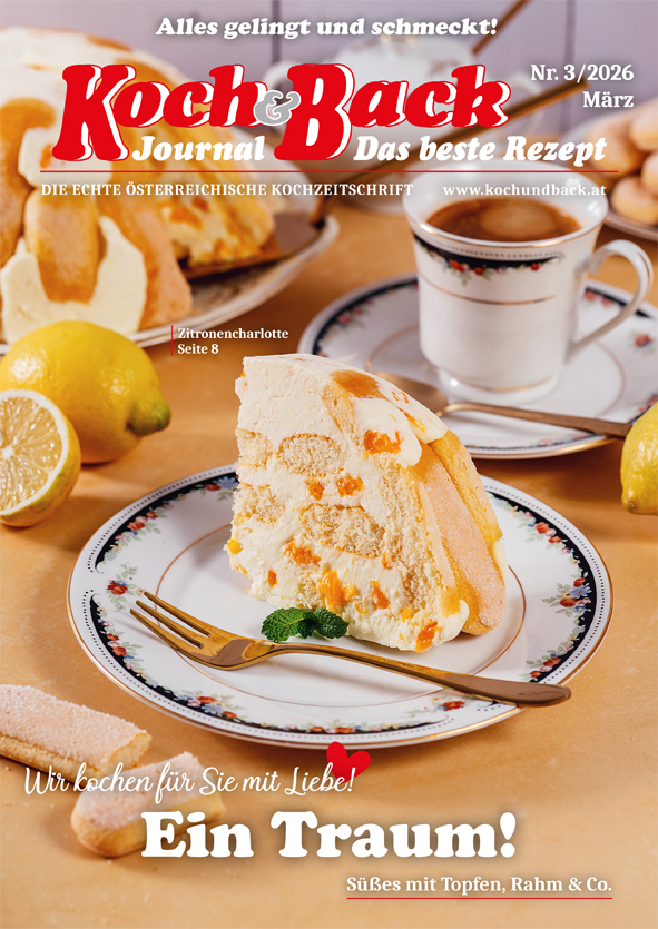 Cover des Koch & Back Journals 3/26 mit einem Teller und einem Tortenstück und Gabel darauf, dahinter eine Tasse Kaffee und Zitronen, davor eine zerbrochene Biskotte