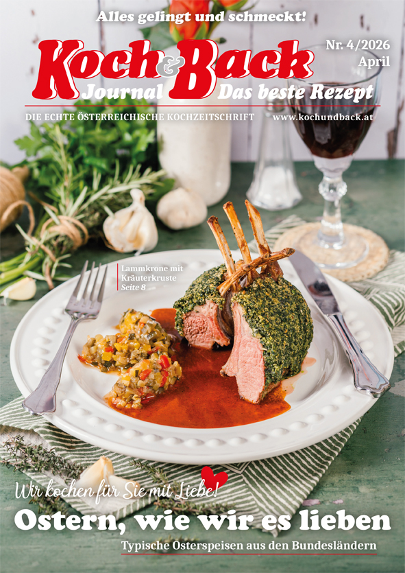 Cover des Koch&Back Journals mit einem gedeckten Tisch, Besteck, Glas und Teller, auf welchem Fleisch, Soße und Beilagen liegen; im Hintergrund u.a. Knoblauchzehe und Petersilie
