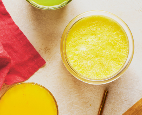 Man sieht drei Gläser von oben, eines mit einem grünen, eines mit einem gelben und eines mit einem orangen Saft befüllt.