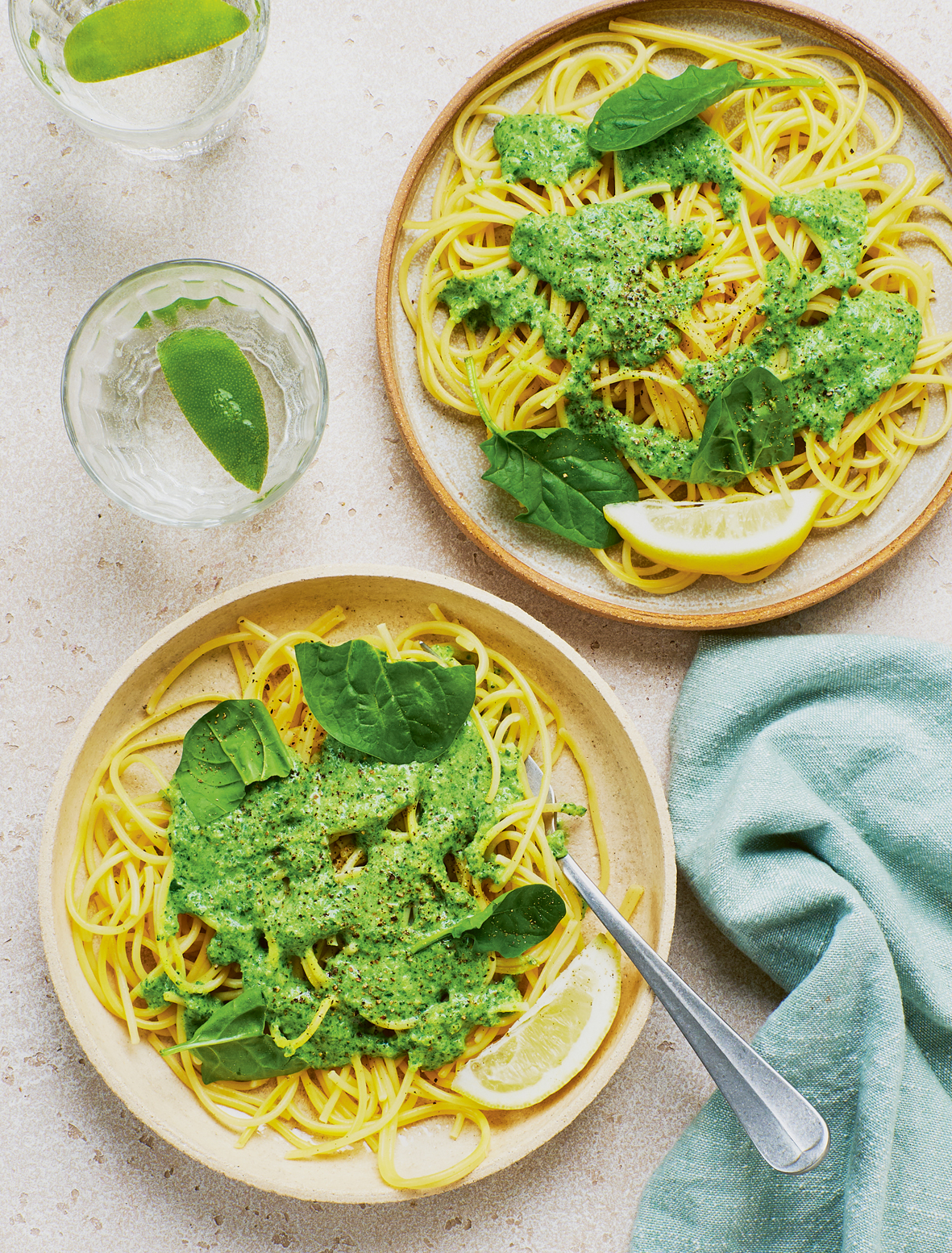 Man sieht zwei Teller von oben. Darauf Spaghetti mit Brokkoli-Brennnessel-Pesto angerichtet und mit jeweils einem Basilikumblatt garniert. Daneben stehen zwei Wassergläser, daneben liegt eine blaue Serviette. Man sieht zwei Teller von oben. Darauf Spaghetti mit Brokkoli-Brennnessel-Pesto angerichtet und mit jeweils einem Basilikumblatt garniert. Daneben stehen zwei Wassergläser, daneben liegt eine blaue Serviette.